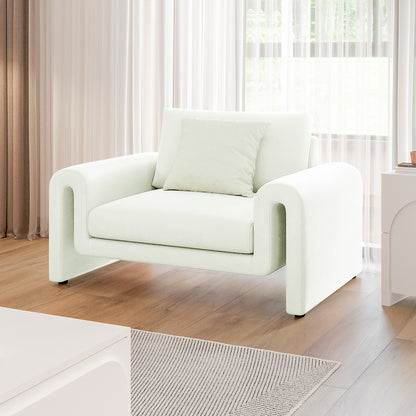 Celyn Curved Velvet Single Sofa Accent Chair in Cream with soft, rounded design, paired with a matching pillow, sits on light-toned hardwood flooring with sheer curtains diffusing natural light behind.