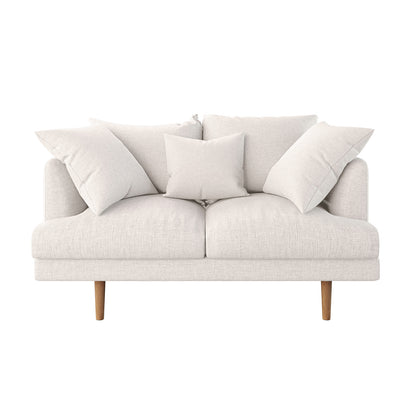 Colton 2 Seater Fabric Sofa with Rug - Cream White features a cream loveseat with plush cushions, three back pillows, and tapered wooden legs, offering a chic, contemporary aesthetic.