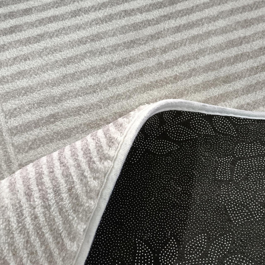 Colton 2 Seater Fabric Sofa with Rug - Cream White close-up showing a fluffy, striped white rug with a flipped corner revealing black non-slip backing, displayed on light grey carpet.