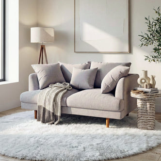 Colton 2-Seater Fabric Sofa in Stone with plush cushions, solid wood legs, and a knitted throw in a bright living room