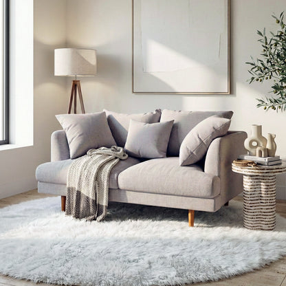Colton 2-Seater Fabric Sofa in Stone with plush cushions, solid wood legs, and a knitted throw in a bright living room