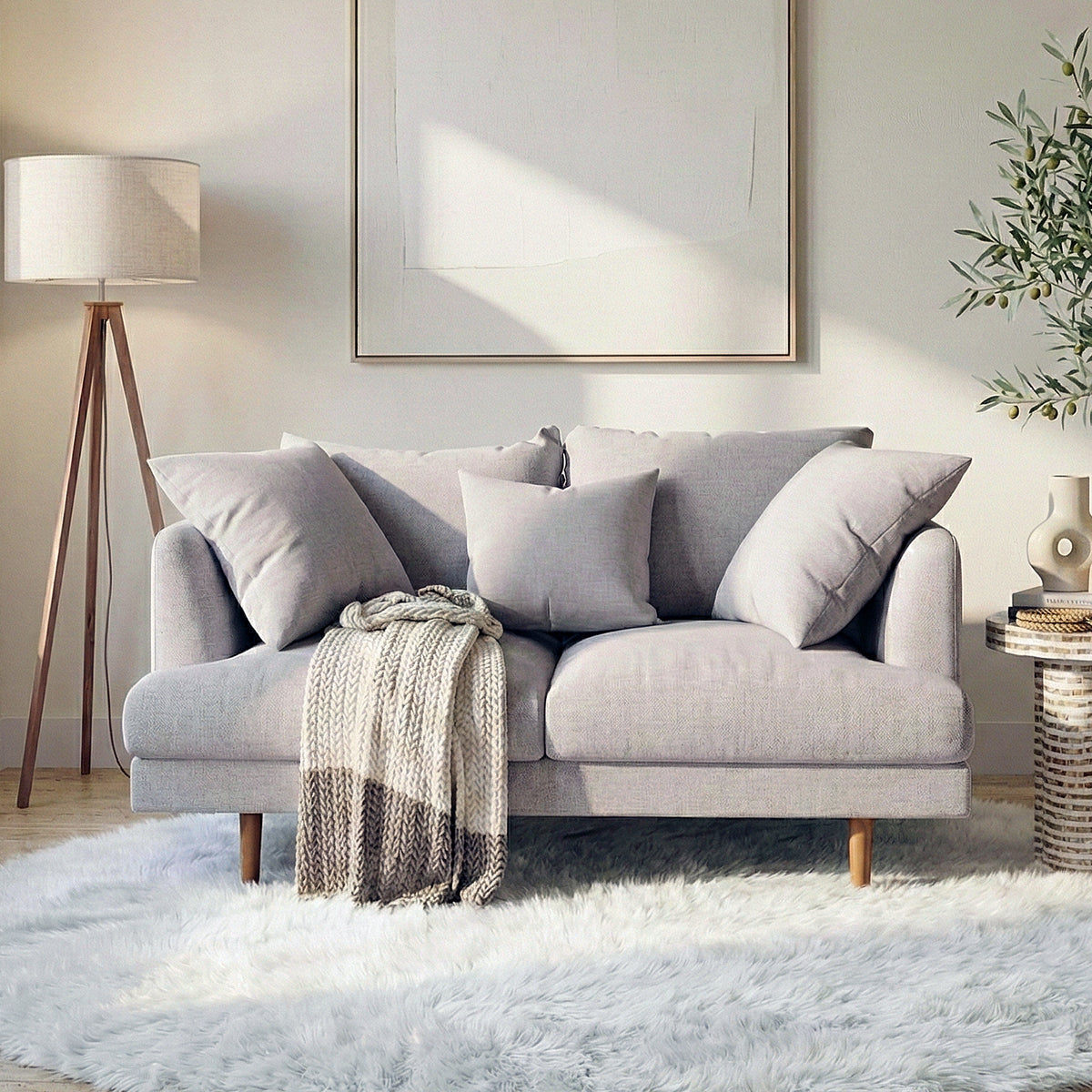 Colton 2-Seater Fabric Sofa in Stone with plush cushions, solid wood legs, and a knitted throw on a white shag rug