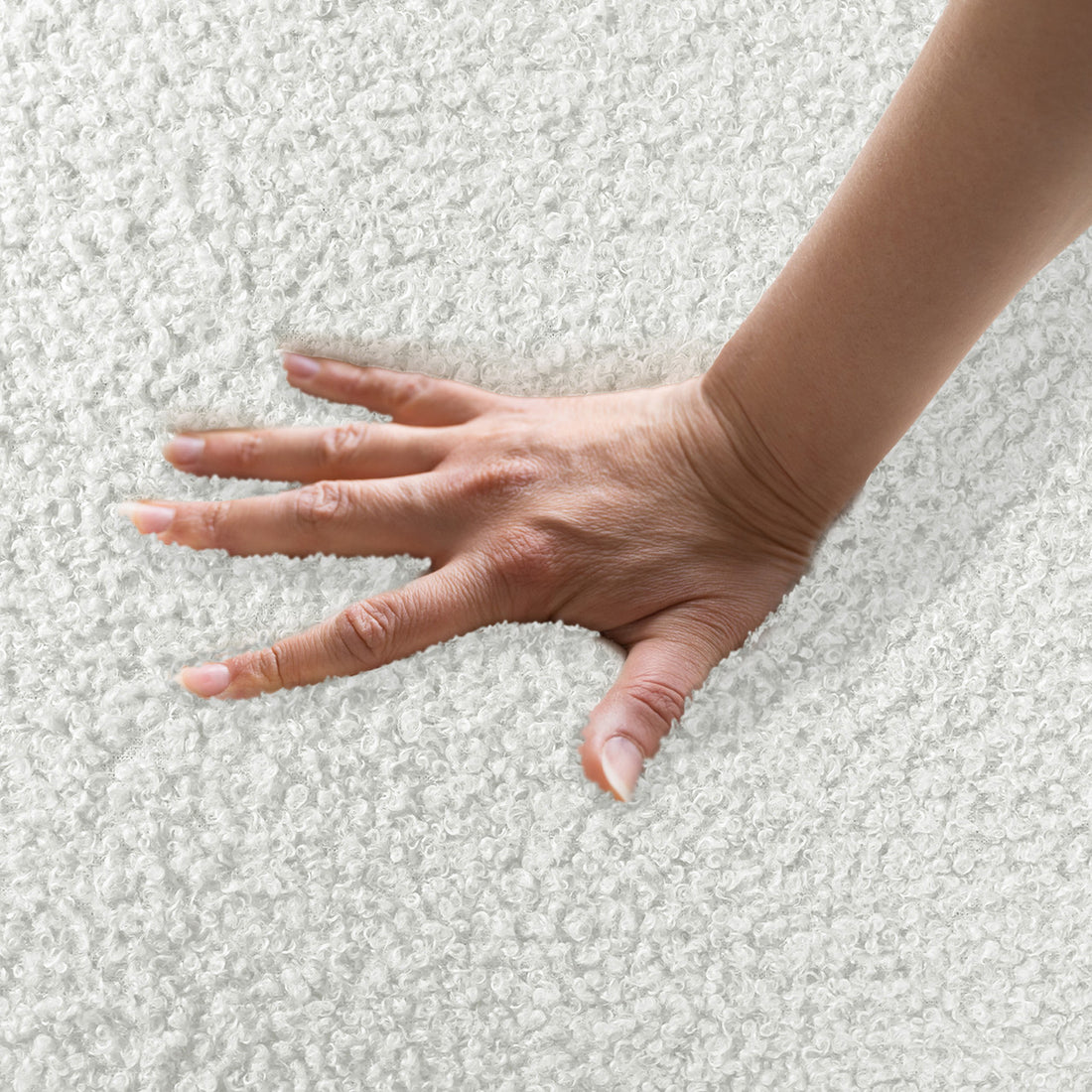 Hand pressing into soft boucle fabric, demonstrating plushness of Corina 4 Seater Modular Boucle Sofa in Cream White, highlighting its luxurious texture and inviting comfort.