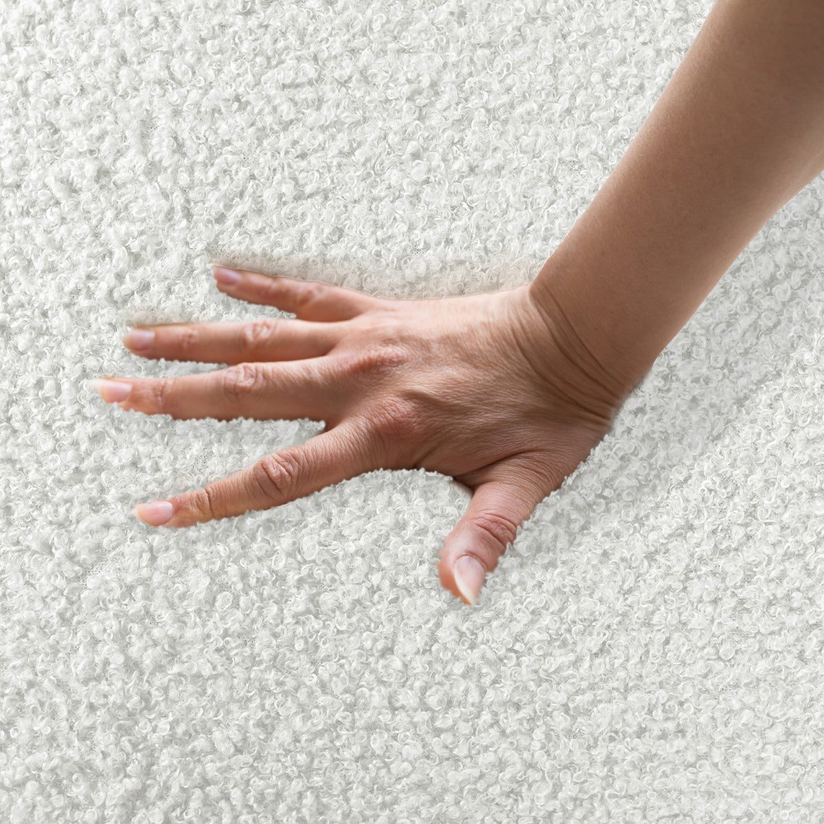 Hand pressing into soft boucle fabric, demonstrating plushness of Corina 4 Seater Modular Boucle Sofa in Cream White, highlighting its luxurious texture and inviting comfort.