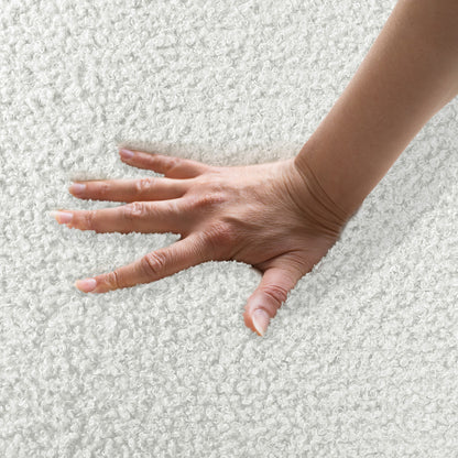 Hand pressing into soft boucle fabric, demonstrating plushness of Corina 4 Seater Modular Boucle Sofa in Cream White, highlighting its luxurious texture and inviting comfort.