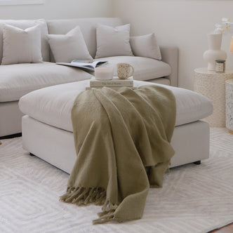 Close-up of the Millie Fabric Ottoman Modular Sofa in warm light grey, showcasing its plush, deep seat and sturdy build, positioned invitingly on a couch, highlighting its luxurious fabric texture.