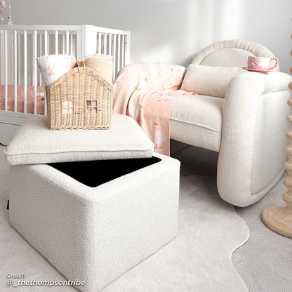 Cream bouclé rocking chair with curved back and matching storage ottoman with lid open, shown in nursery setting with white