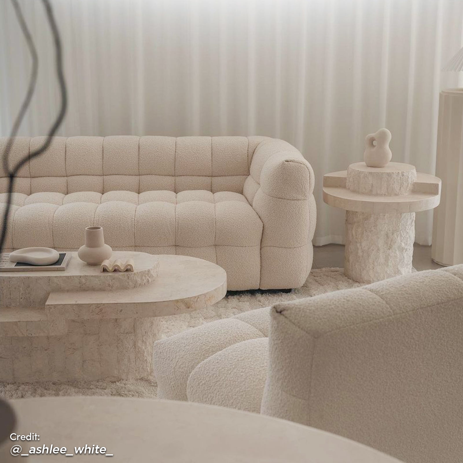Norah 3 Seater Boucle Sofa in Cream White, featuring plush grid-tufting and boucle upholstery, is showcased with a matching lounge chair, stone-look coffee table, and shag-style rug in a serene living room setting.