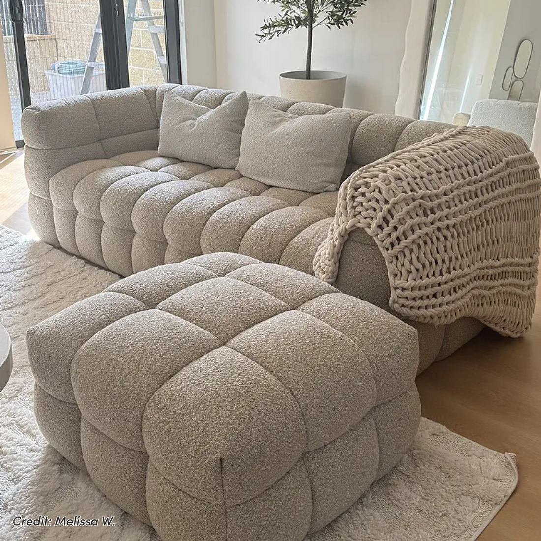 Norah 3 Seater Boucle Sofa in Warm Beige with matching ottoman, chunky knit throw, and two cushions in a bright living space