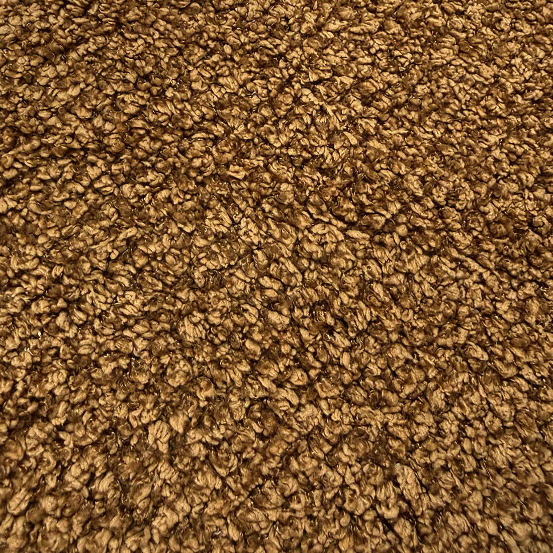 Close-up of mustard brown boucle fabric texture showing woven looped fibres