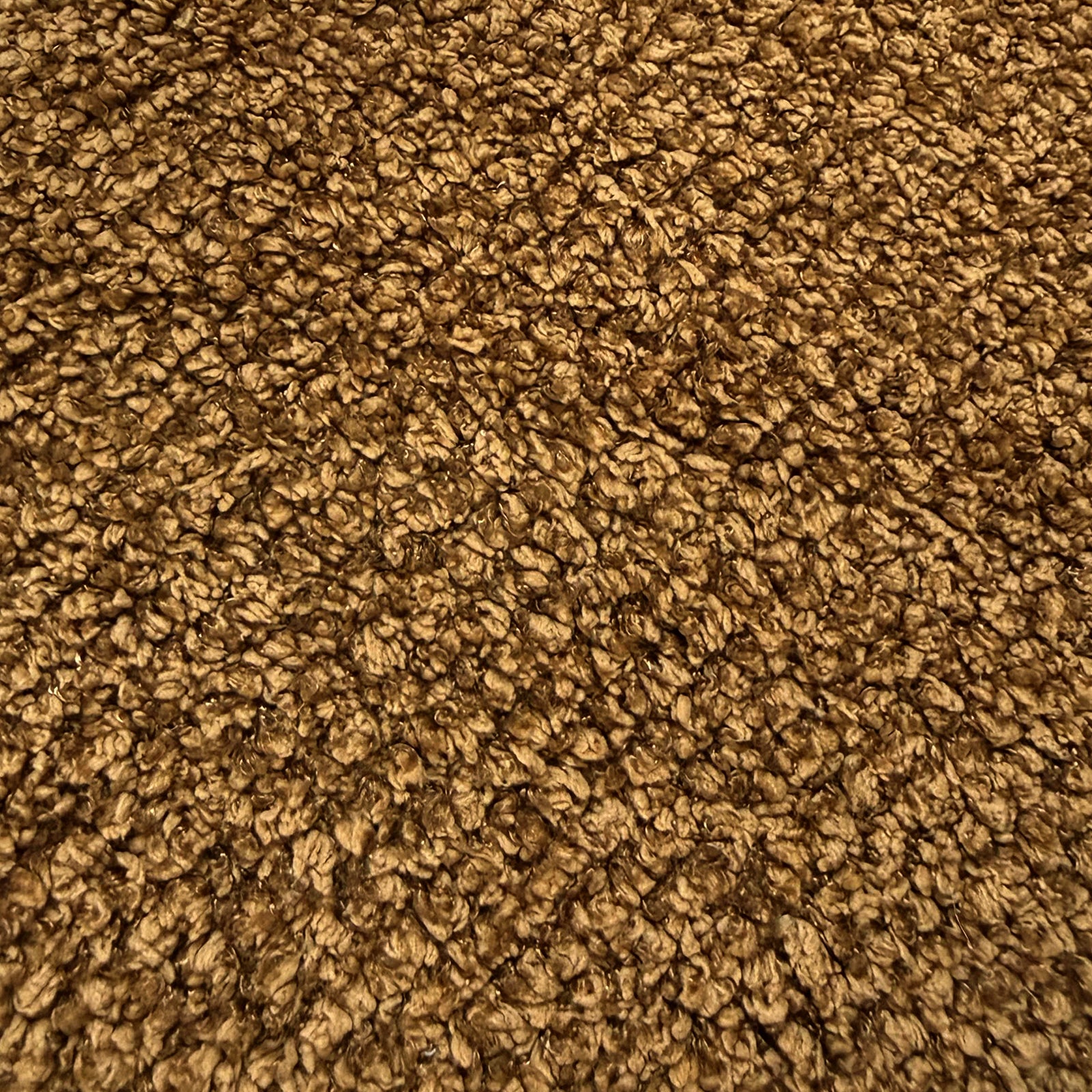 Close-up of mustard brown boucle fabric texture showing woven looped fibres