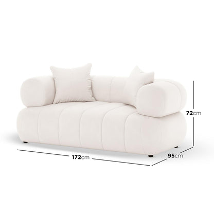 Samira 2 Seater Velvet Lounge in Cream, featuring a modern design with off-white upholstery, cylindrical armrests, and two throw cushions. Dimensions: 172 cm wide, 95 cm deep, 72 cm tall.