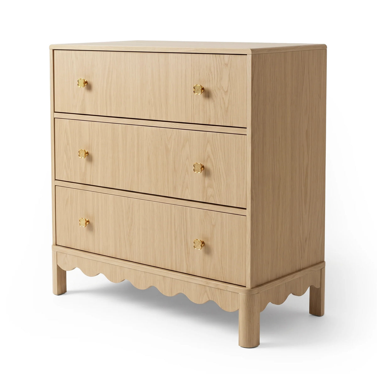 A light oak dresser featuring three spacious drawers, each accented with gold flower-shaped knobs, and finished with a scalloped base detail.