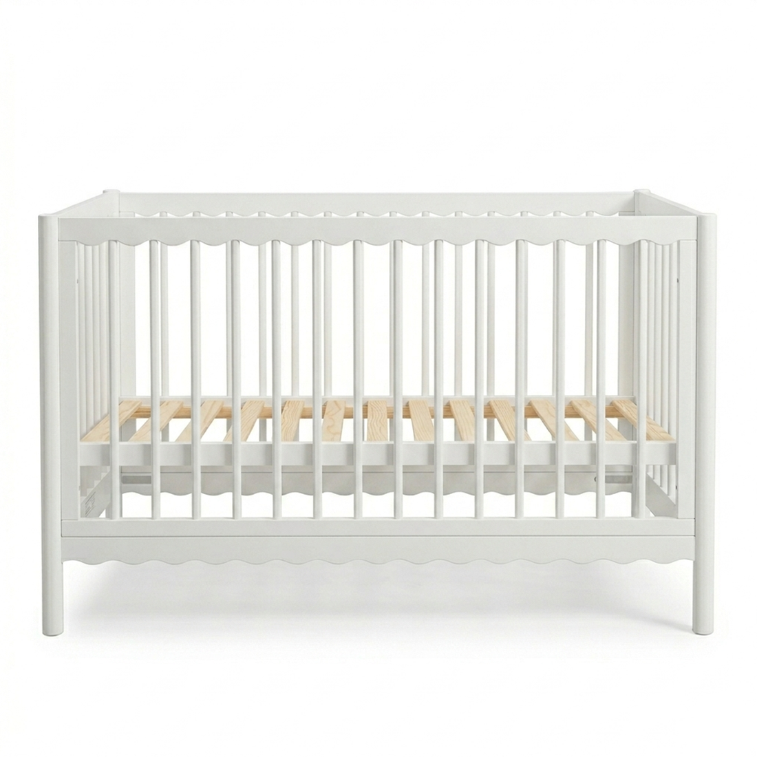 White wooden baby crib with scalloped edges and natural wood mattress slats on a white background