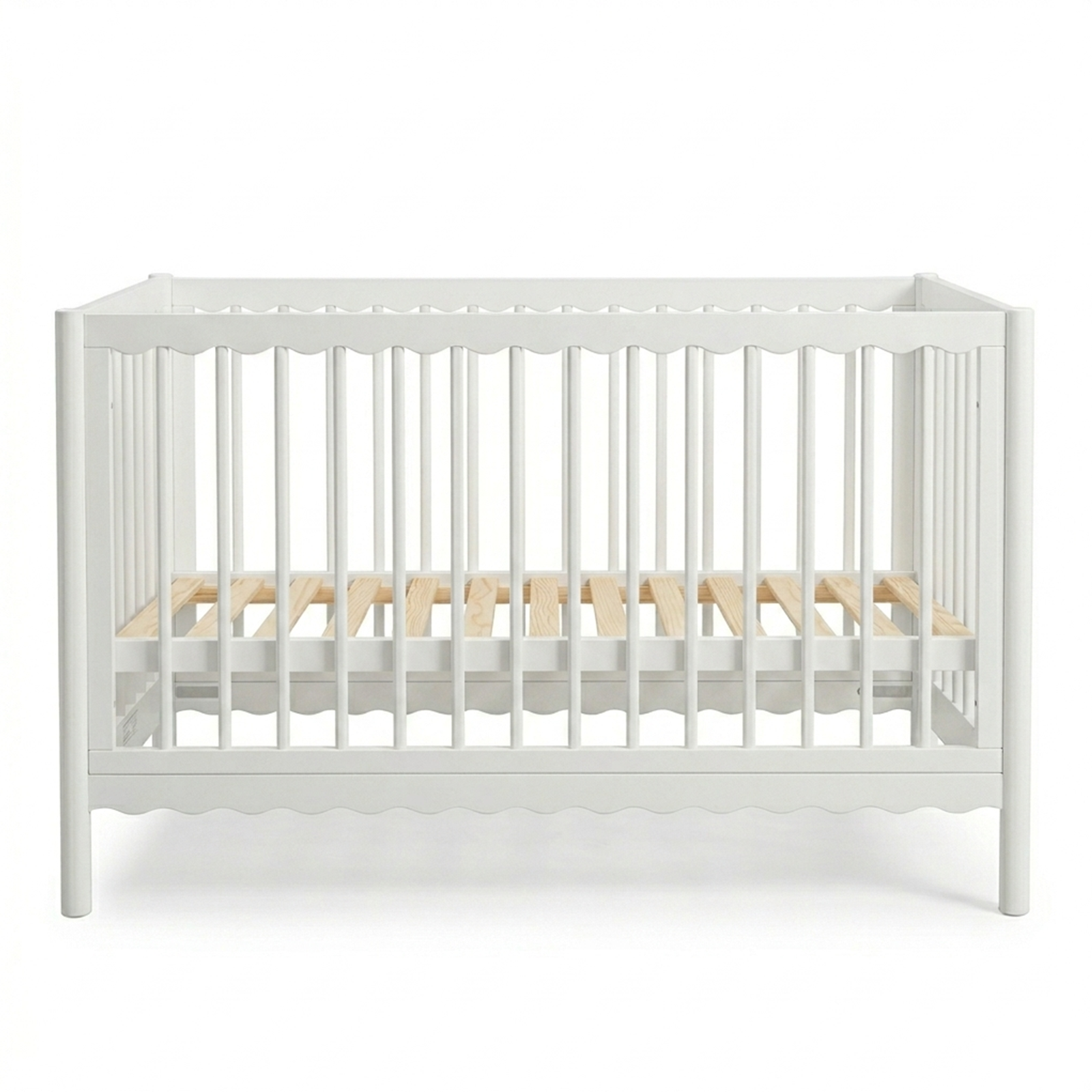White wooden baby crib with scalloped edges and natural wood mattress slats on a white background