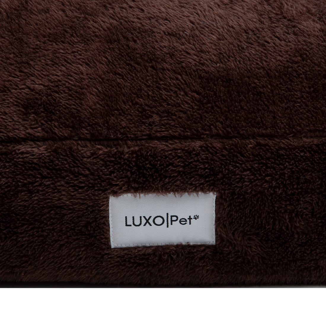 Close-up of brown plush fabric with LuxoPet label on white background