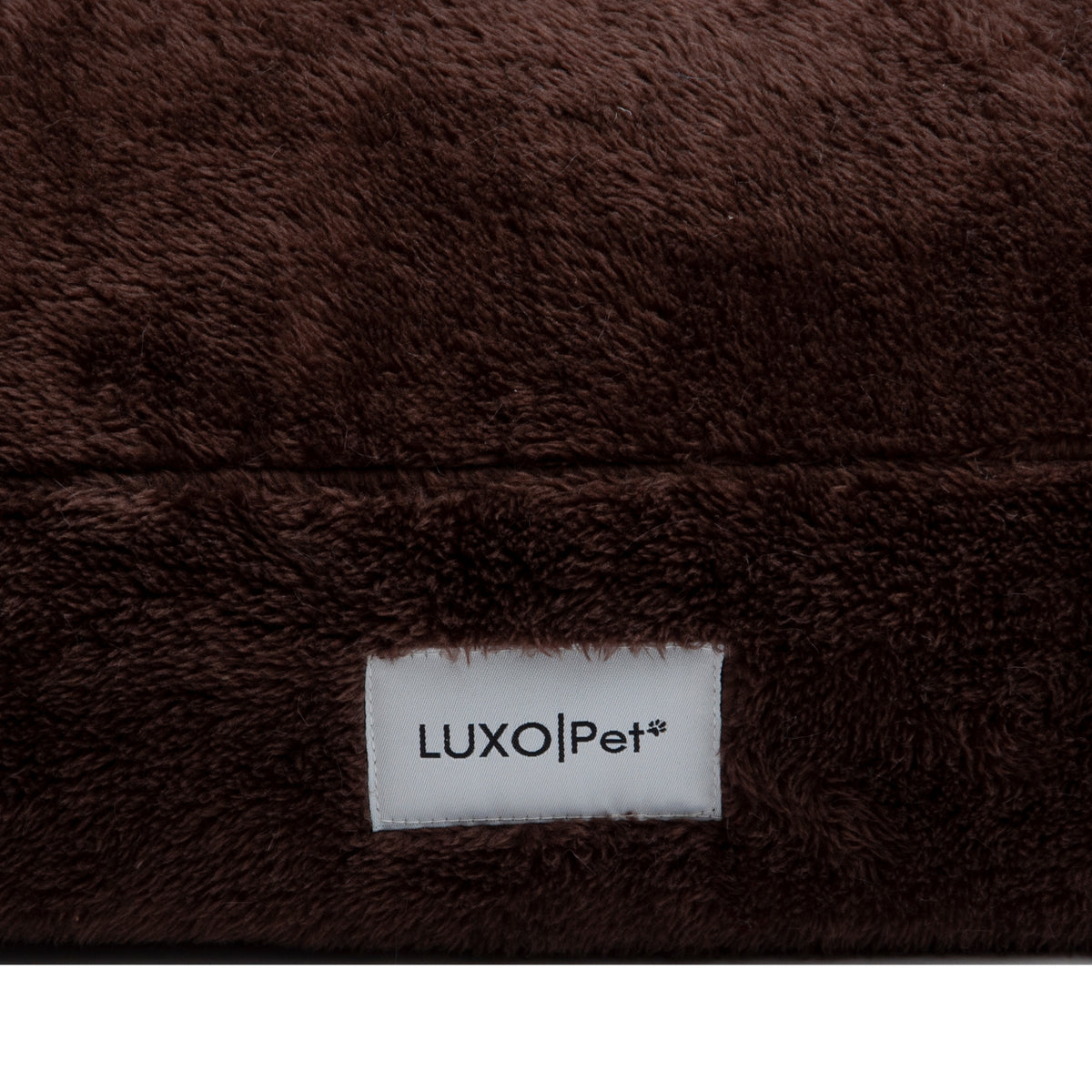 Close-up of brown plush fabric with LuxoPet label on white background