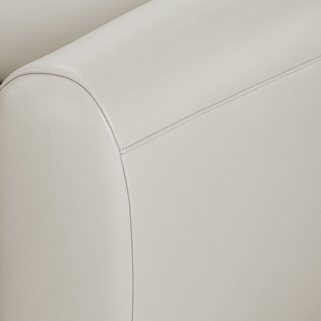 Close-up of a light-colored upholstered sofa armrest with stitching