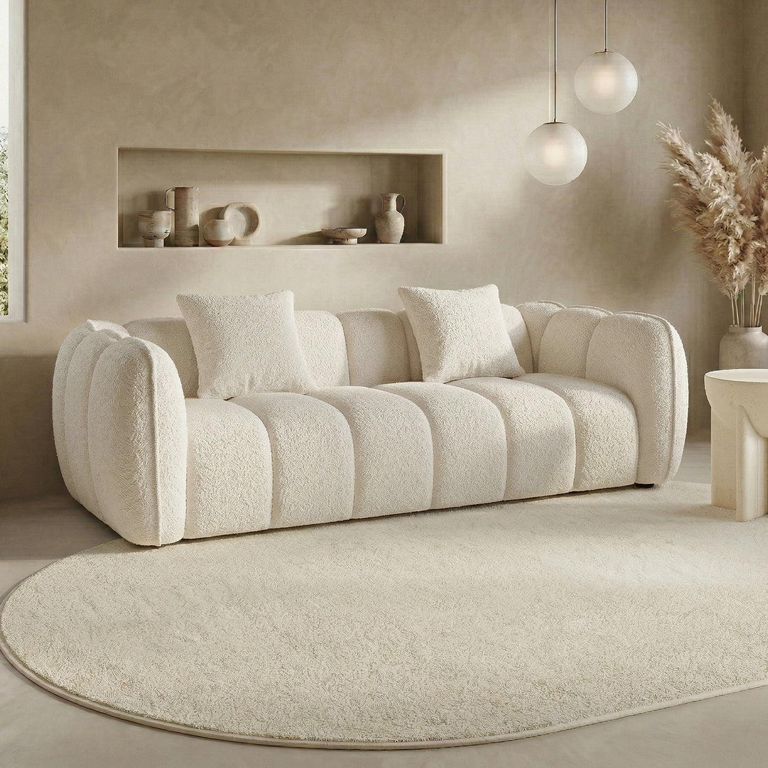 Cream-colored textured sofa with throw pillows in a modern living room setting with pendant lights and a decorative rug