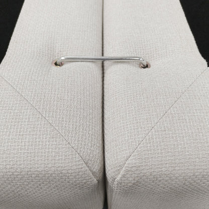 Close-up of beige upholstered cushions joined by a metal connector bar