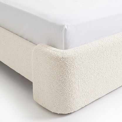 Corner detail of an upholstered bed frame on a white background