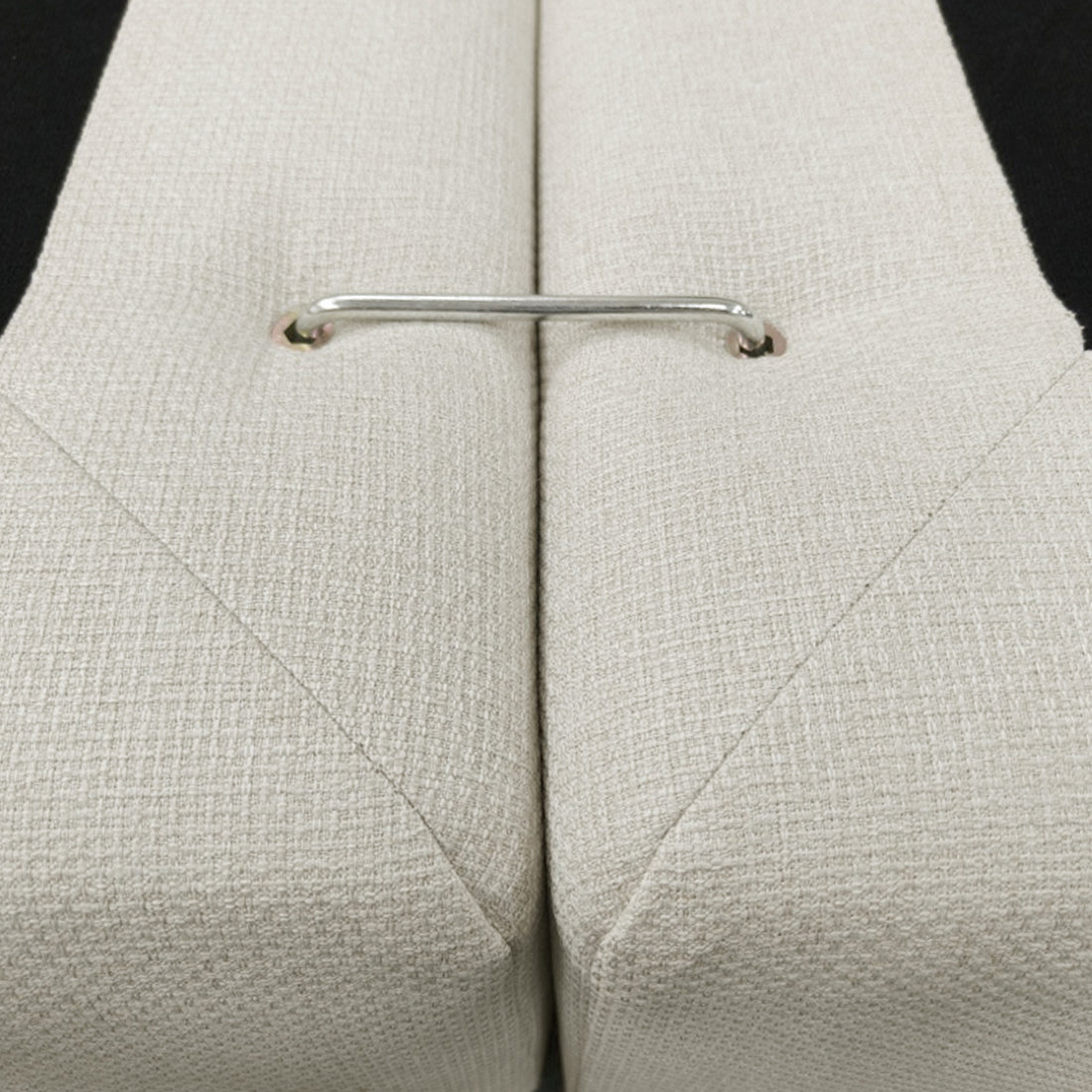 Close-up of beige upholstered cushions with a metal connector