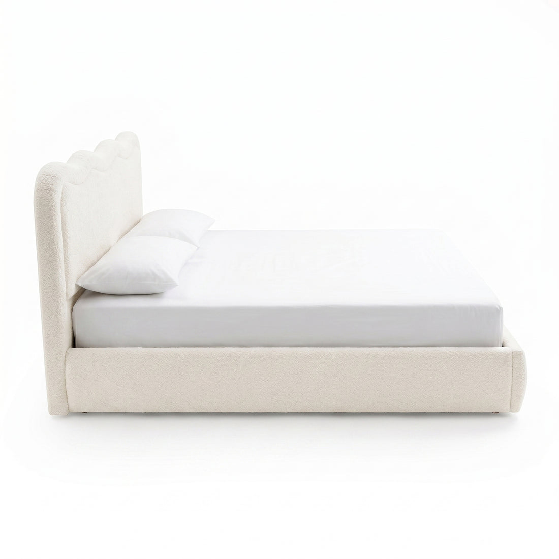 Side profile of an upholstered bed with scalloped headboard on white background