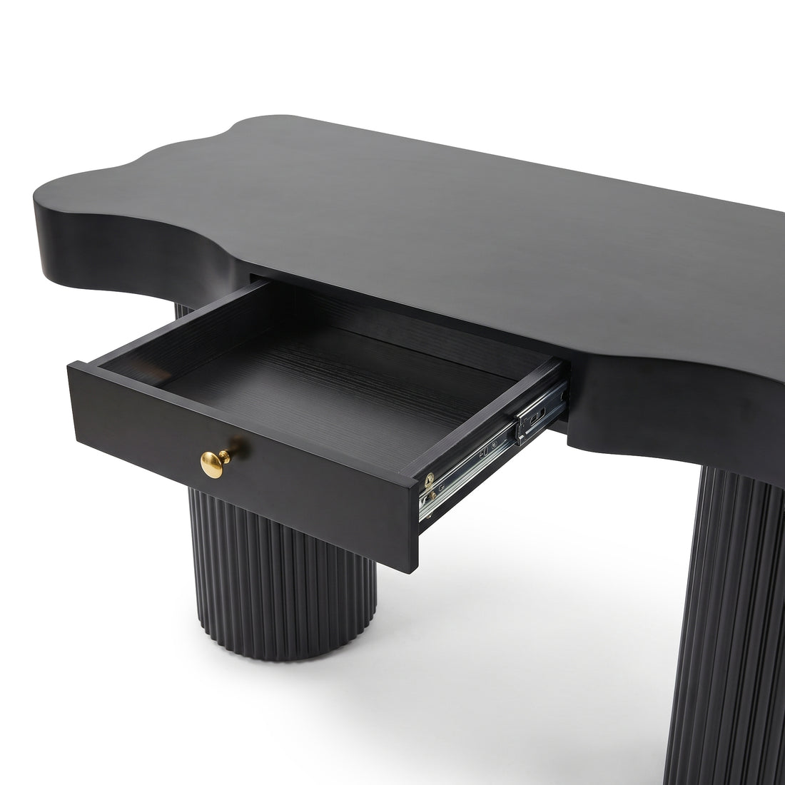 Partial view of a black console table with fluted legs and open drawer on a white background