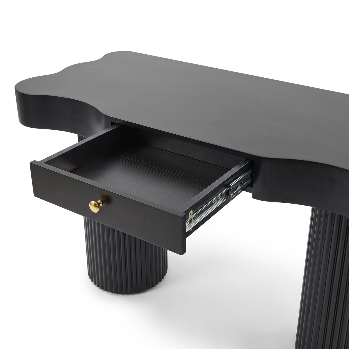 Partial view of a black console table with fluted legs and open drawer on a white background