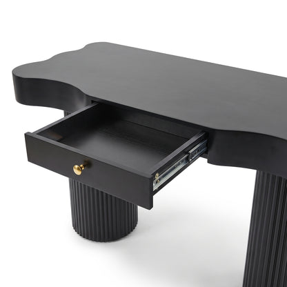 Partial view of a black console table with fluted legs and open drawer on a white background