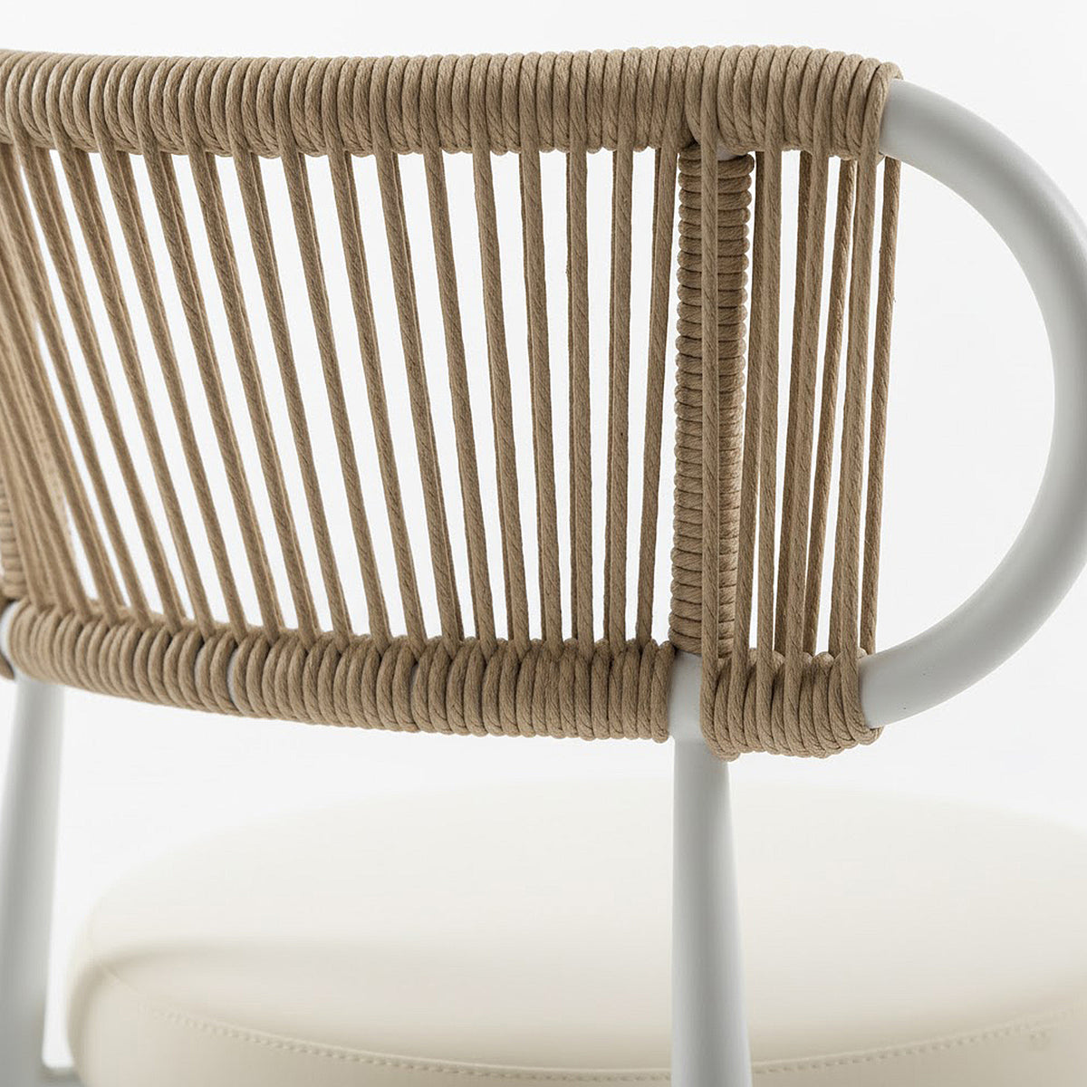 Cabria 7 Piece Sintered Stone Outdoor Dining Set in Beige featuring a modern chair with a white tubular metal frame and natural-tan rope-wrapped backrest, complemented by a cream-colored seat cushion.