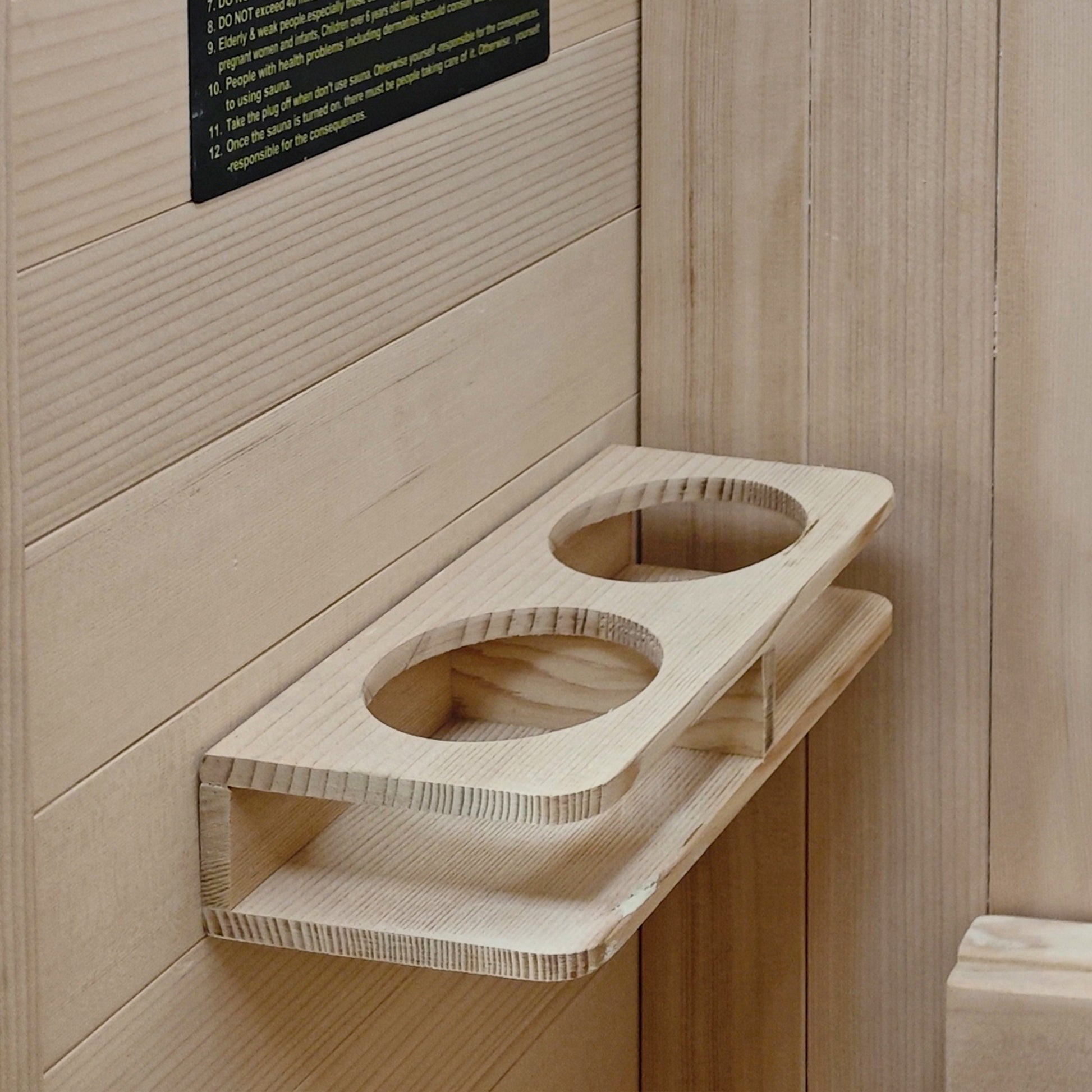 Wooden double-cup holder or rack mounted on a wood-paneled wall.