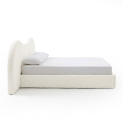 Side profile of upholstered bed with curved headboard on white background
