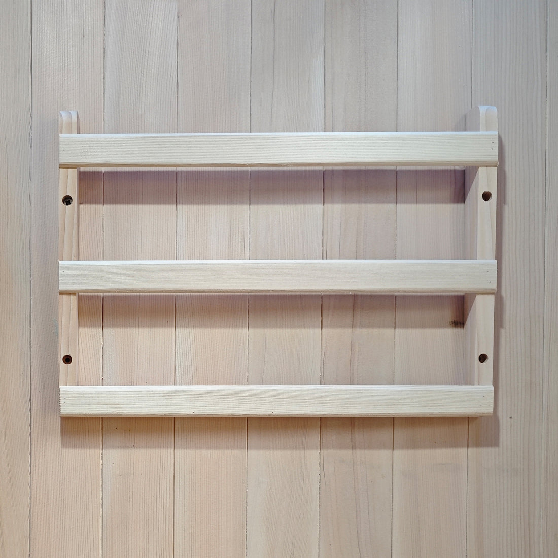 Light wood two-shelf wall rack mounted on a wood-paneled wall
