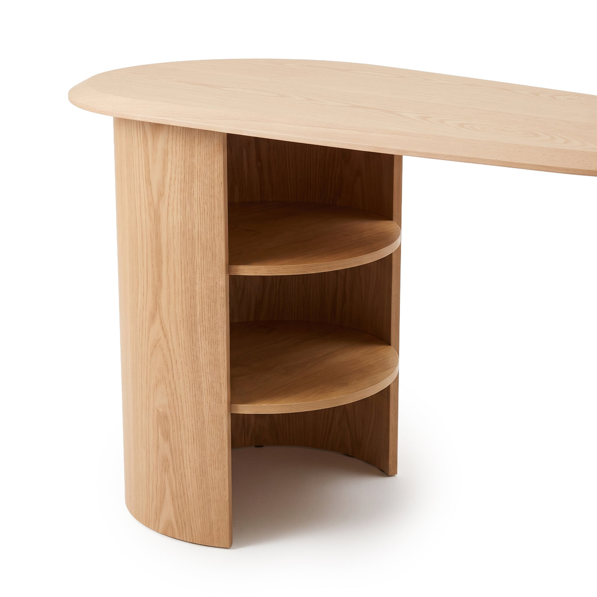 Close view of one rounded shelving end of a light wood desk on a white background.