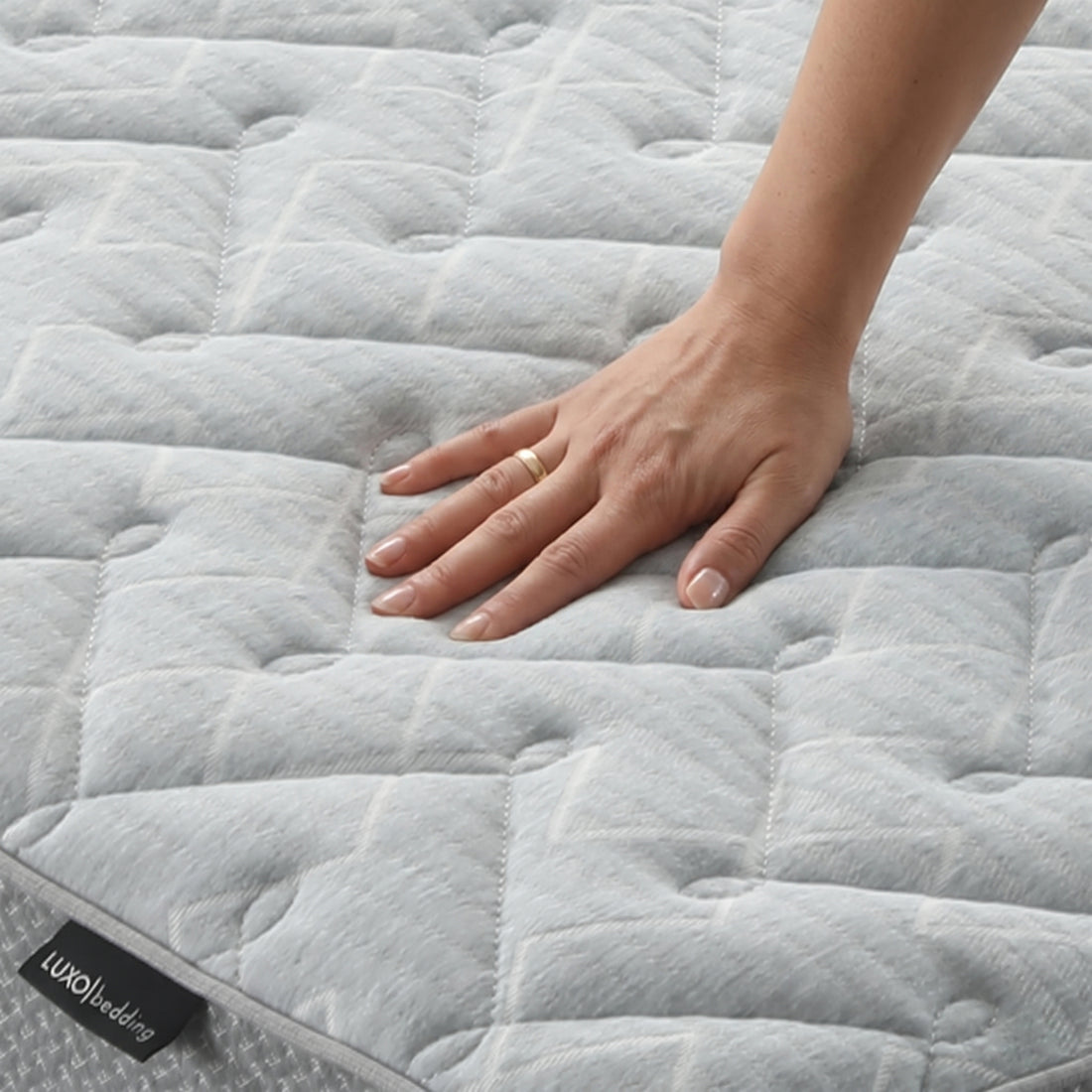 Close-up of mattress surface with a hand pressing down