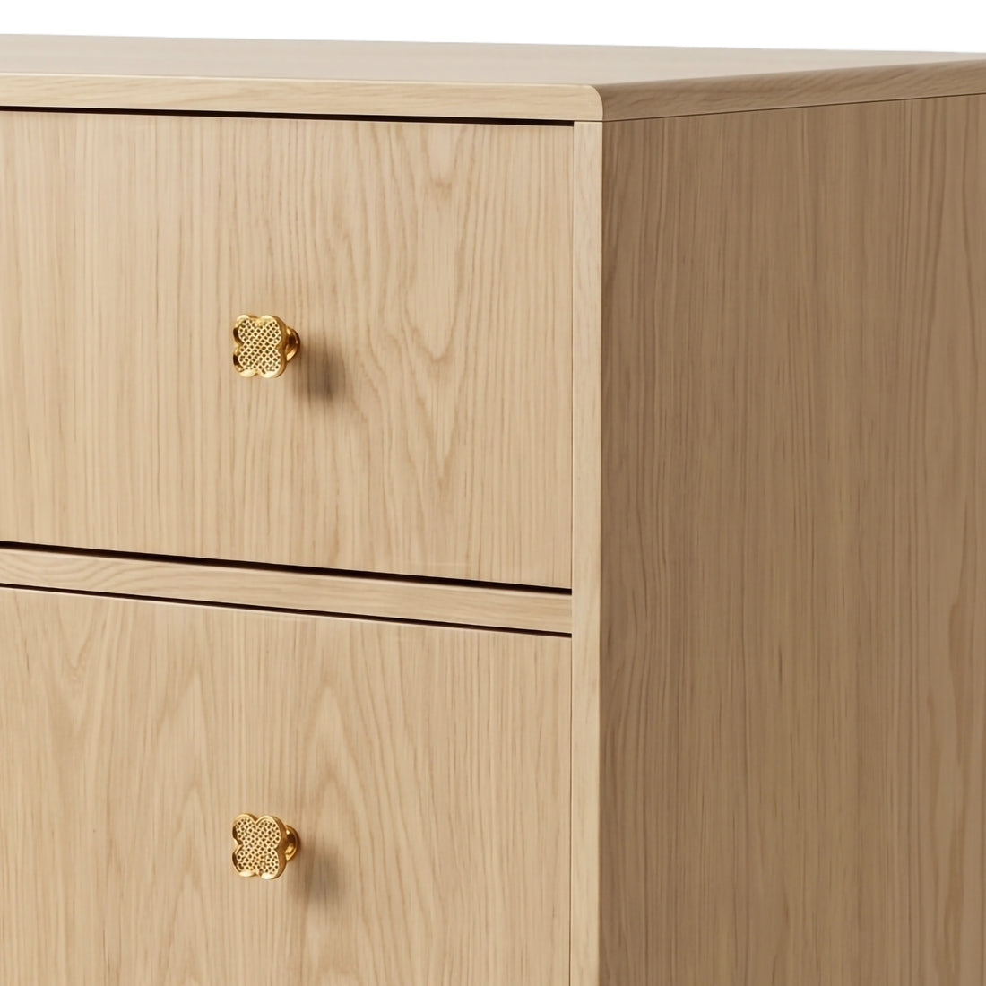 Close-up of upper drawers of wooden dresser showing gold quatrefoil knobs on white background