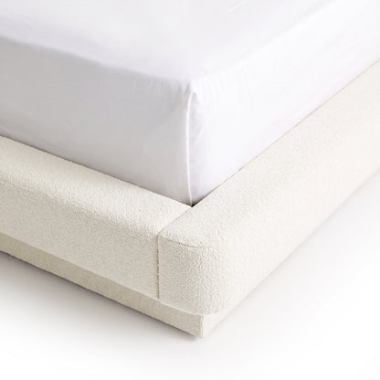 Close-up of the corner of an upholstered bed frame on a white background