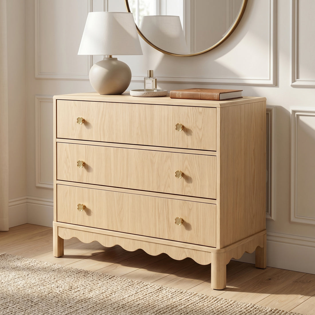 Three-drawer light wood dresser styled in a cozy room with a lamp, mirror, and books
