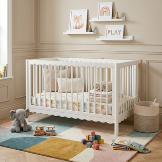 White wooden crib in a decorated nursery room with toys and blankets