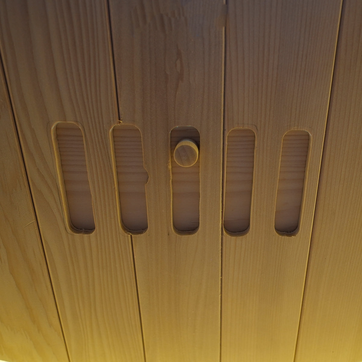 Close-up detail of a wooden surface with vertical slots and a knob