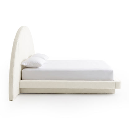 Side view of a modern upholstered bed with arched headboard on a white background