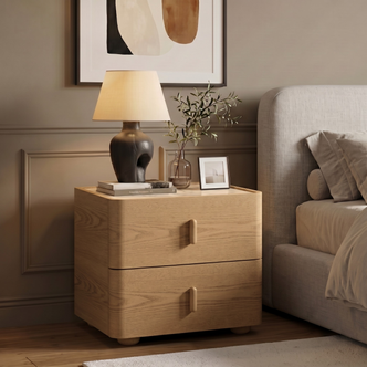Light wood two-drawer nightstand styled beside a bed in a modern bedroom