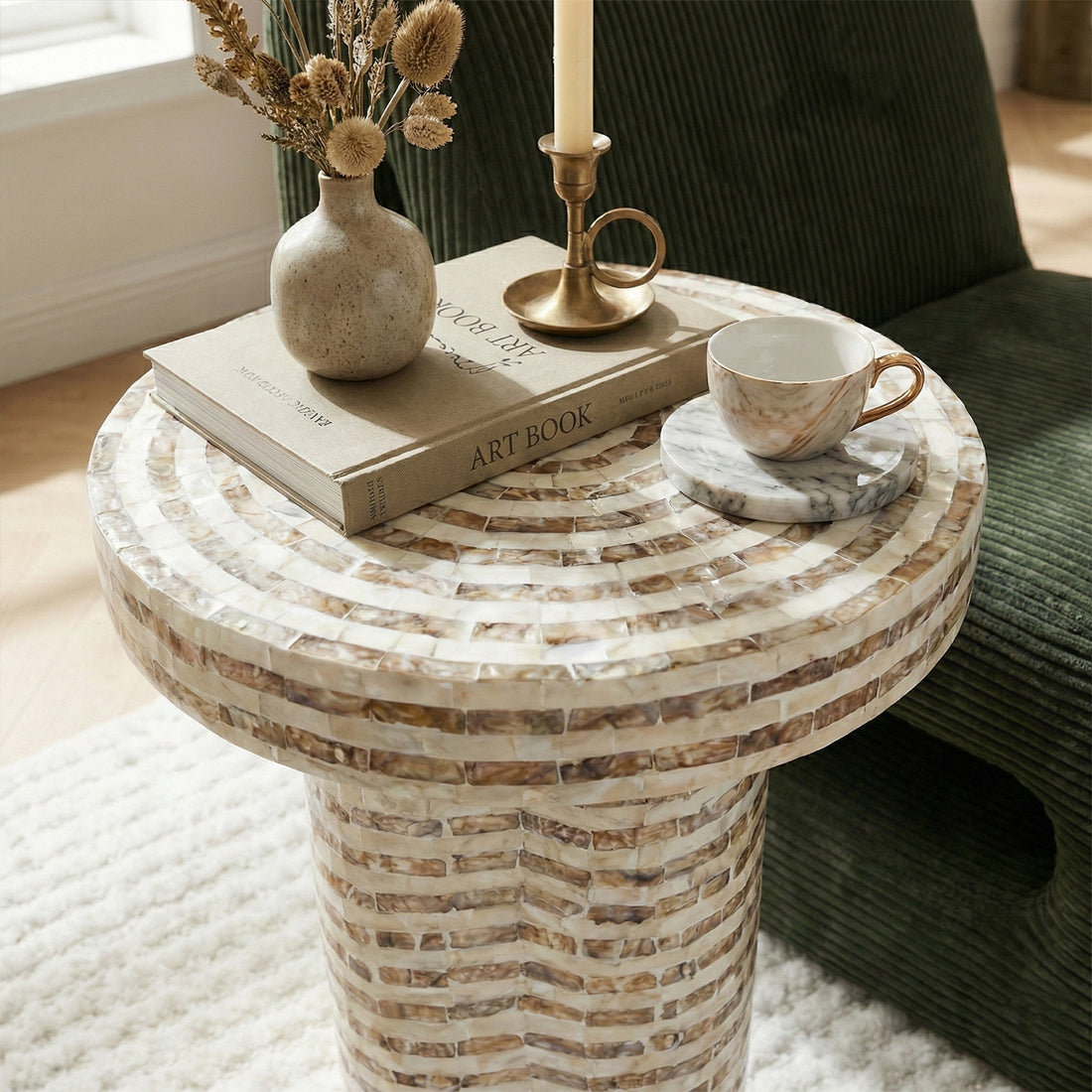 Round mosaic side table with vase and books in living space