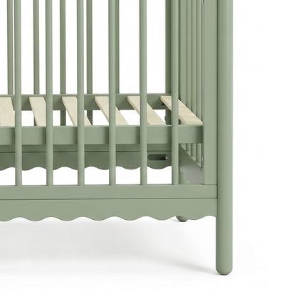 Close-up of crib's slatted base and scalloped edge
