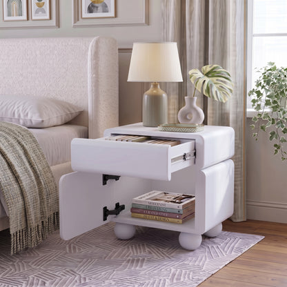 White nightstand with open shelf and drawer styled beside a bed in a bedroom
