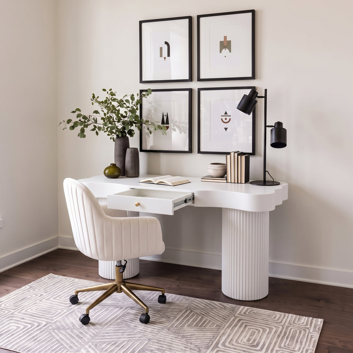 White desk and swivel chair styled in a bright modern home office with art prints and decor