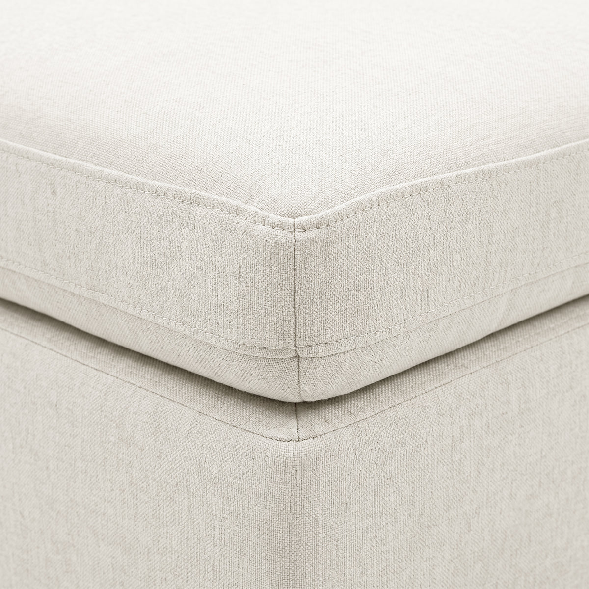 Close-up of cream upholstered cushion corner with stitching and textured fabric