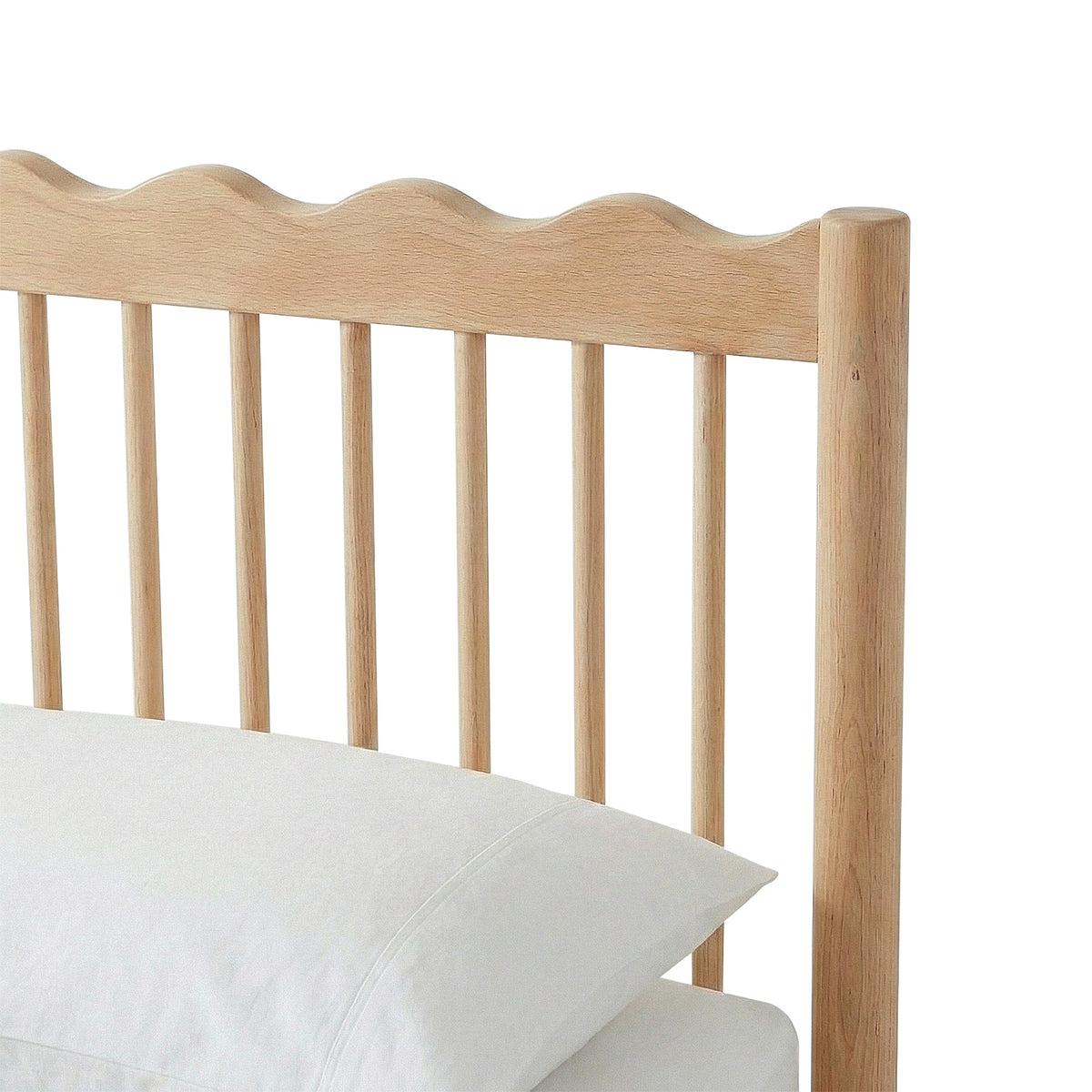 Close-up of bed frame headboard with scalloped edge and two pillows on white background
