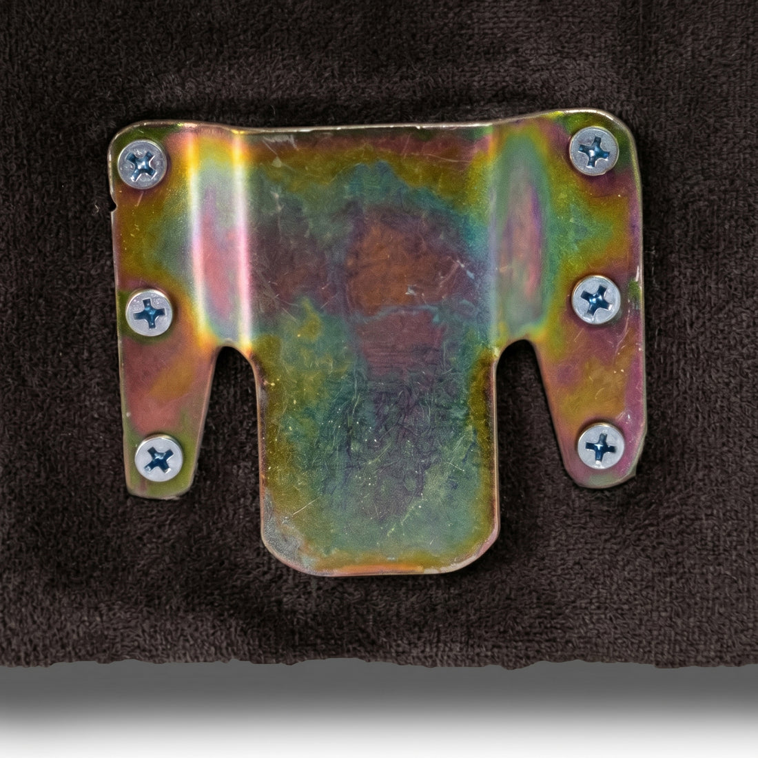 Close-up of iridescent metal bracket on dark upholstered surface